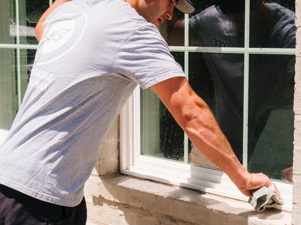 Capital City crew member cleaning a window by hand